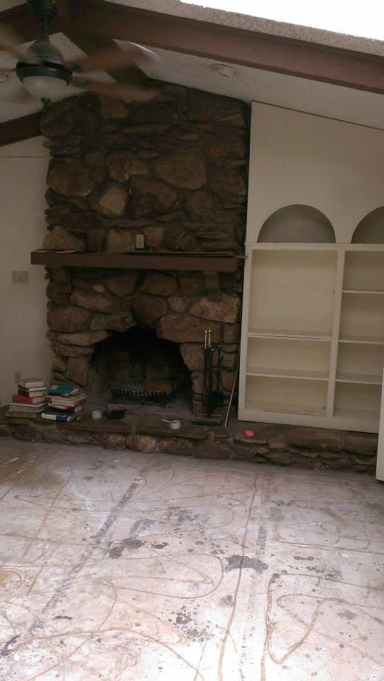 Original outdated living room and rock fireplace before structural remediation.